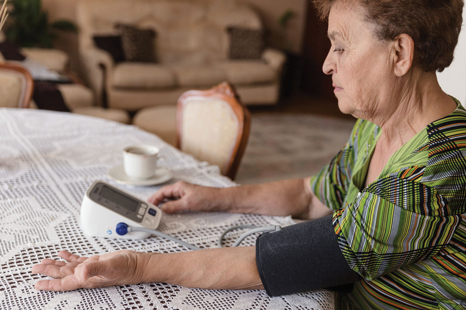photo of a mature woman using a blood pressure cuff to take her own pressure at home