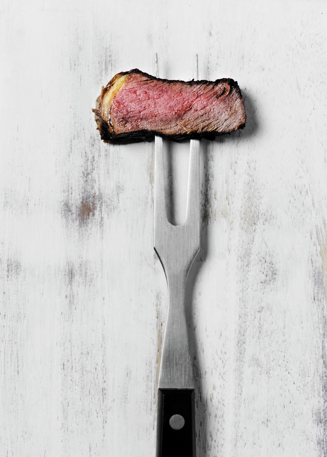 photo of a piece of cooked meat on a two-prong grill fork