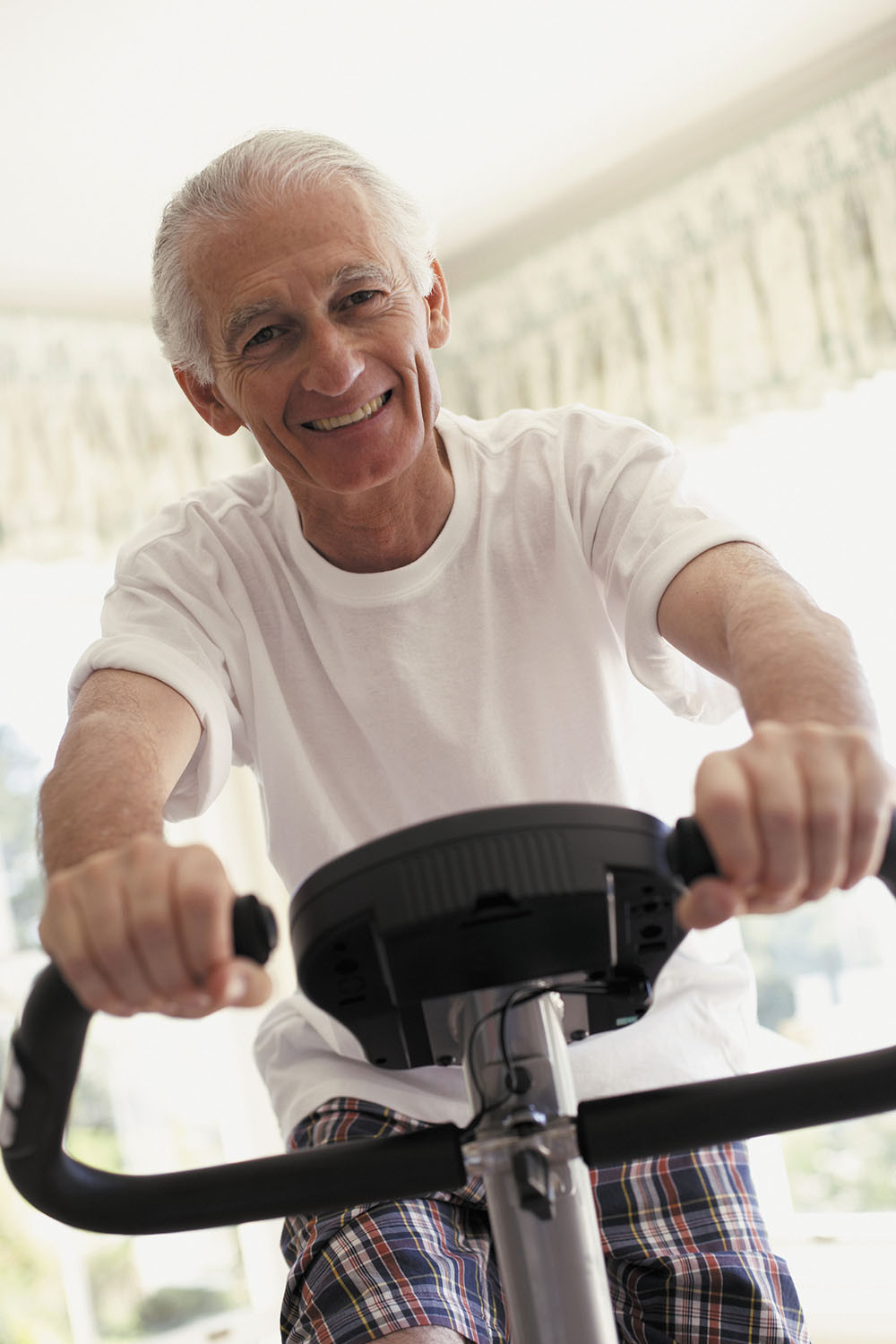 photo of a senior man exercising on a stationary bike in his home