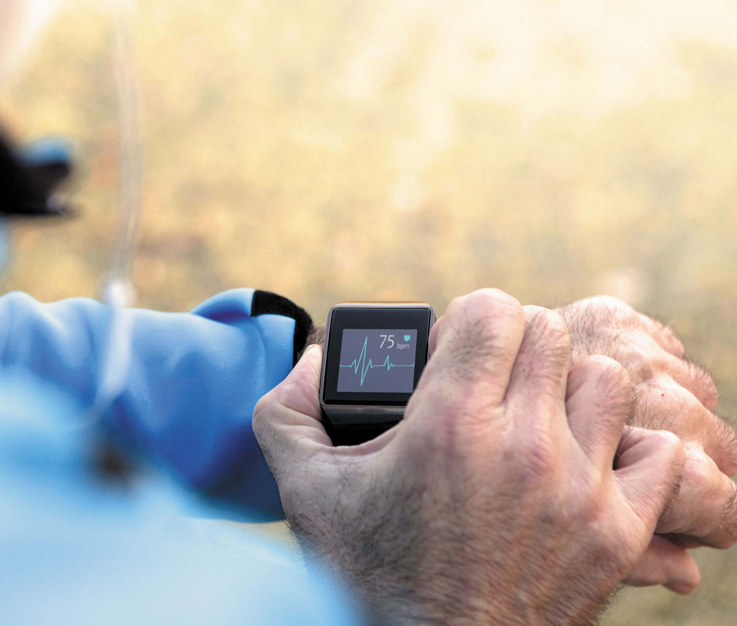 close-up photo of the wrist and hands of a man using a smartwatch that is showing a heart monitoring function
