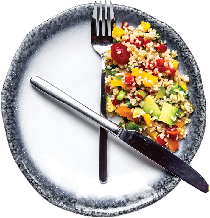 photo of a plate with a fork and knife arranged like clock hands at 12 and 4, with food in the area between them