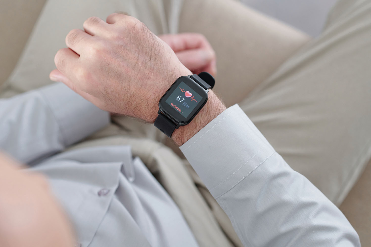 tightly cropped photo ofthe wrist of a man wearing a heart monitoring smartwatch