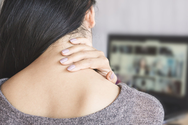 A young woman holding the back of her neck. 