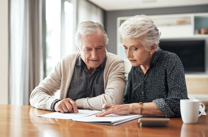 A photo of a senior couple sitting together and going through their finances at home.