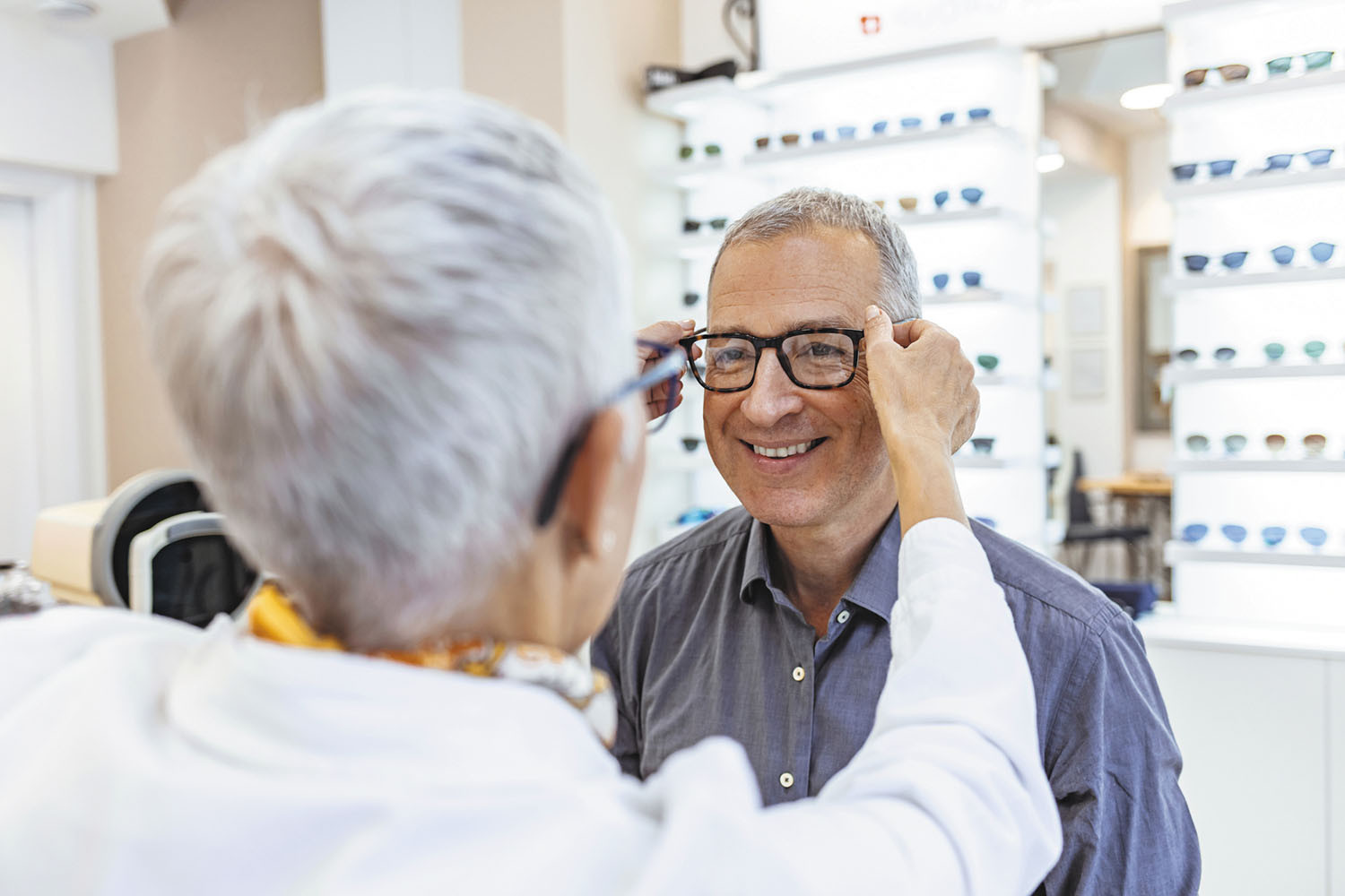 photo of a man smiling as he is being fitted for eyeglasses in an optical shop