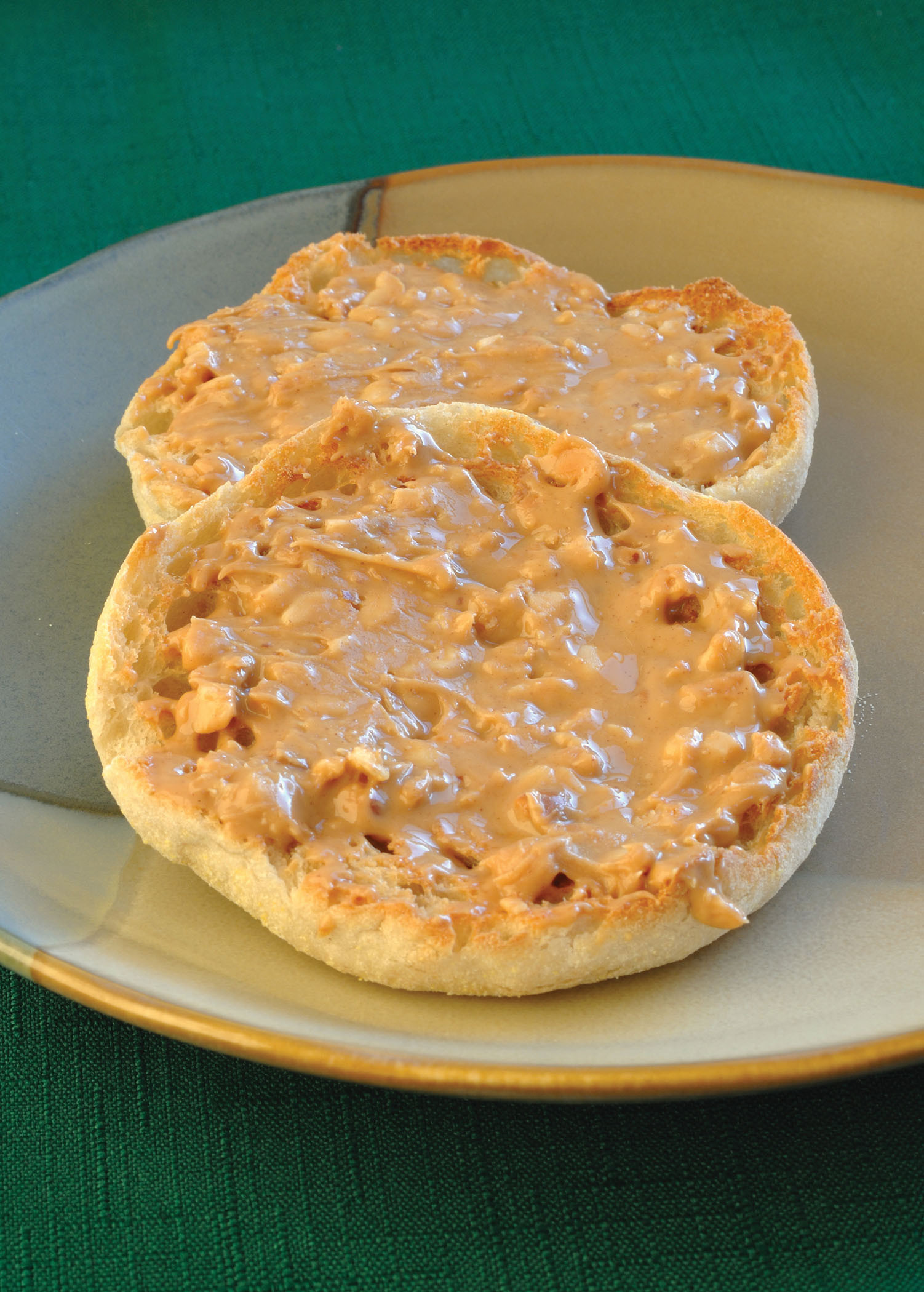 photo of an english muffin with peanut butter spread on it