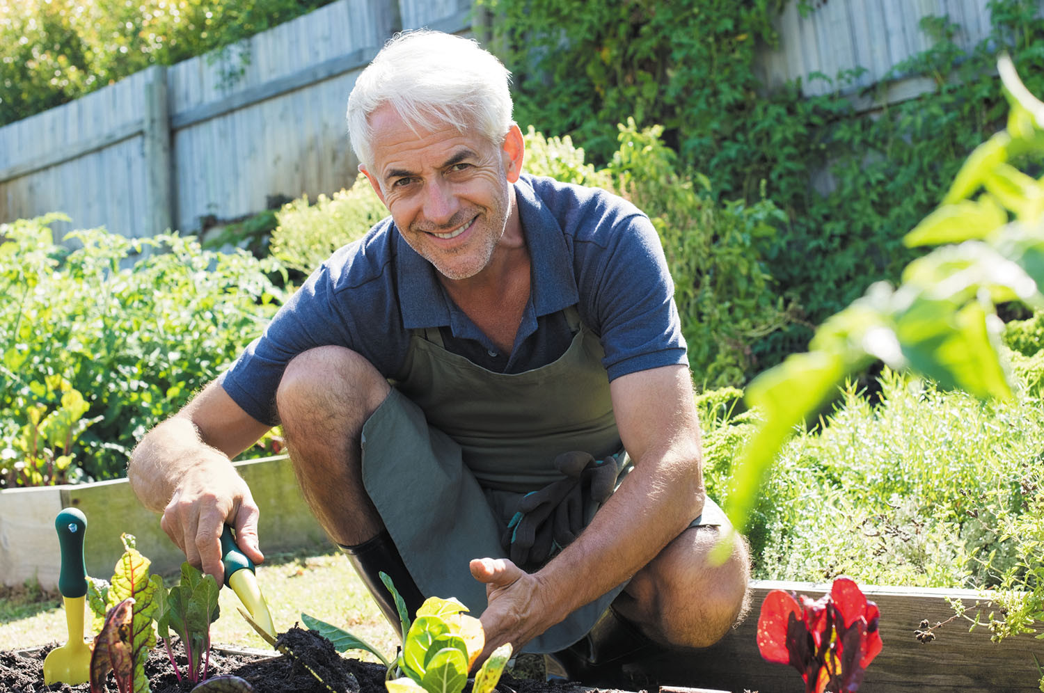photo of a mature man crouching while working in a garden