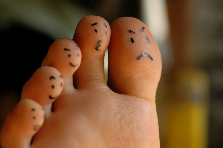 La pointe d'un pied et cinq orteils avec différentes émotions comme un visage triste, inquiet ou heureux dessiné au stylo ;  arrière-plan flou