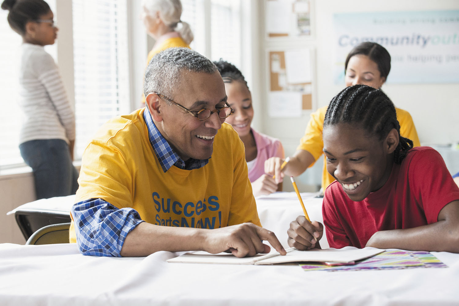 photo of a mature man working with a teenager in a school classroom