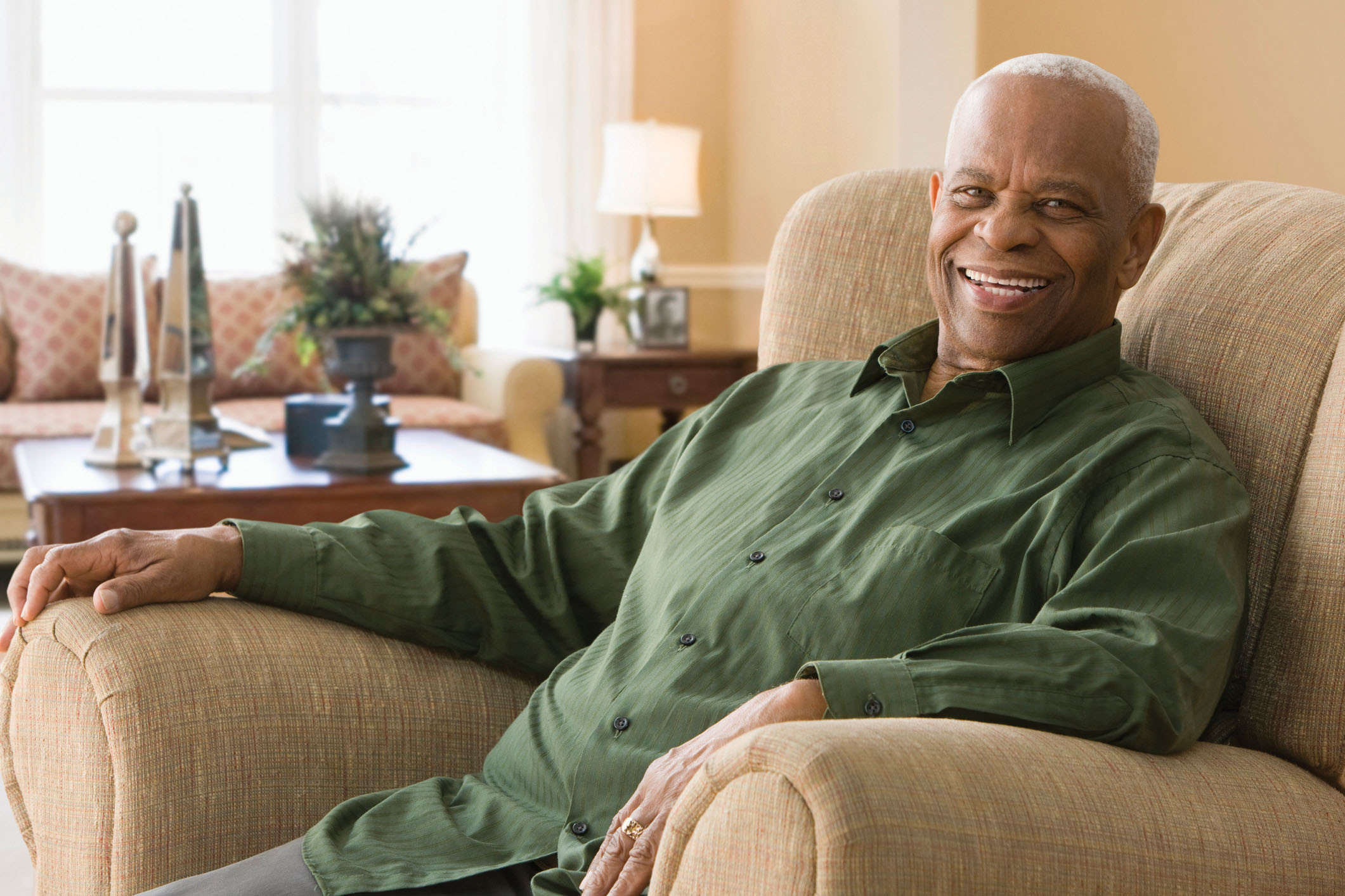 photo of a senior man sitting in a chair in his living room and smiling