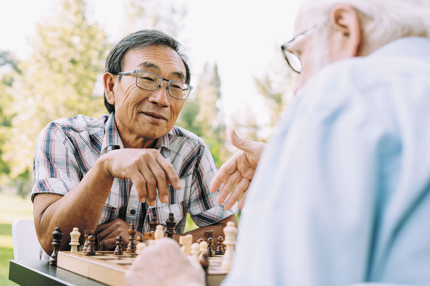 photo of two senior men playing chess outdoors