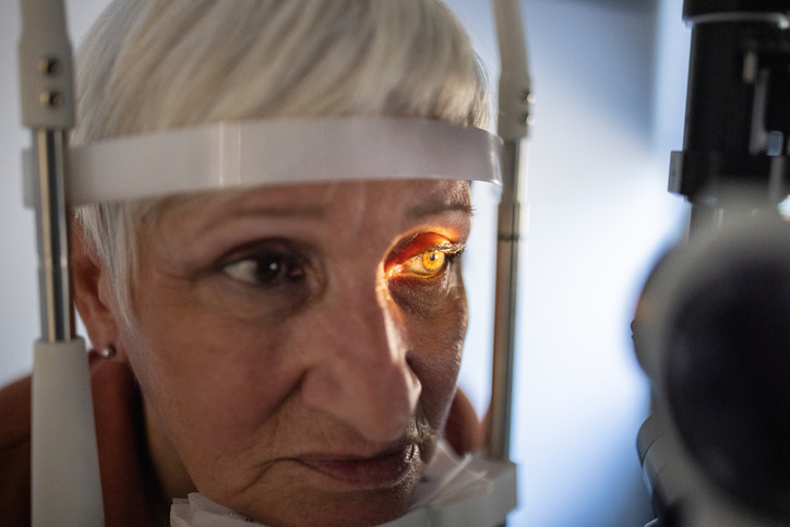 Senior woman undergoing eye exam at ophthalmologist's office.