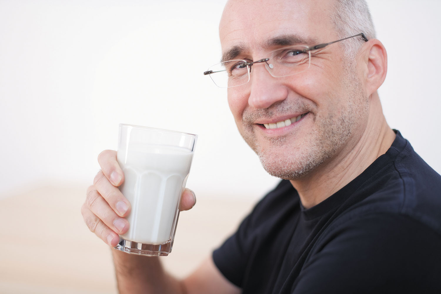 photo of a mature man smiling and holding a glass of milk