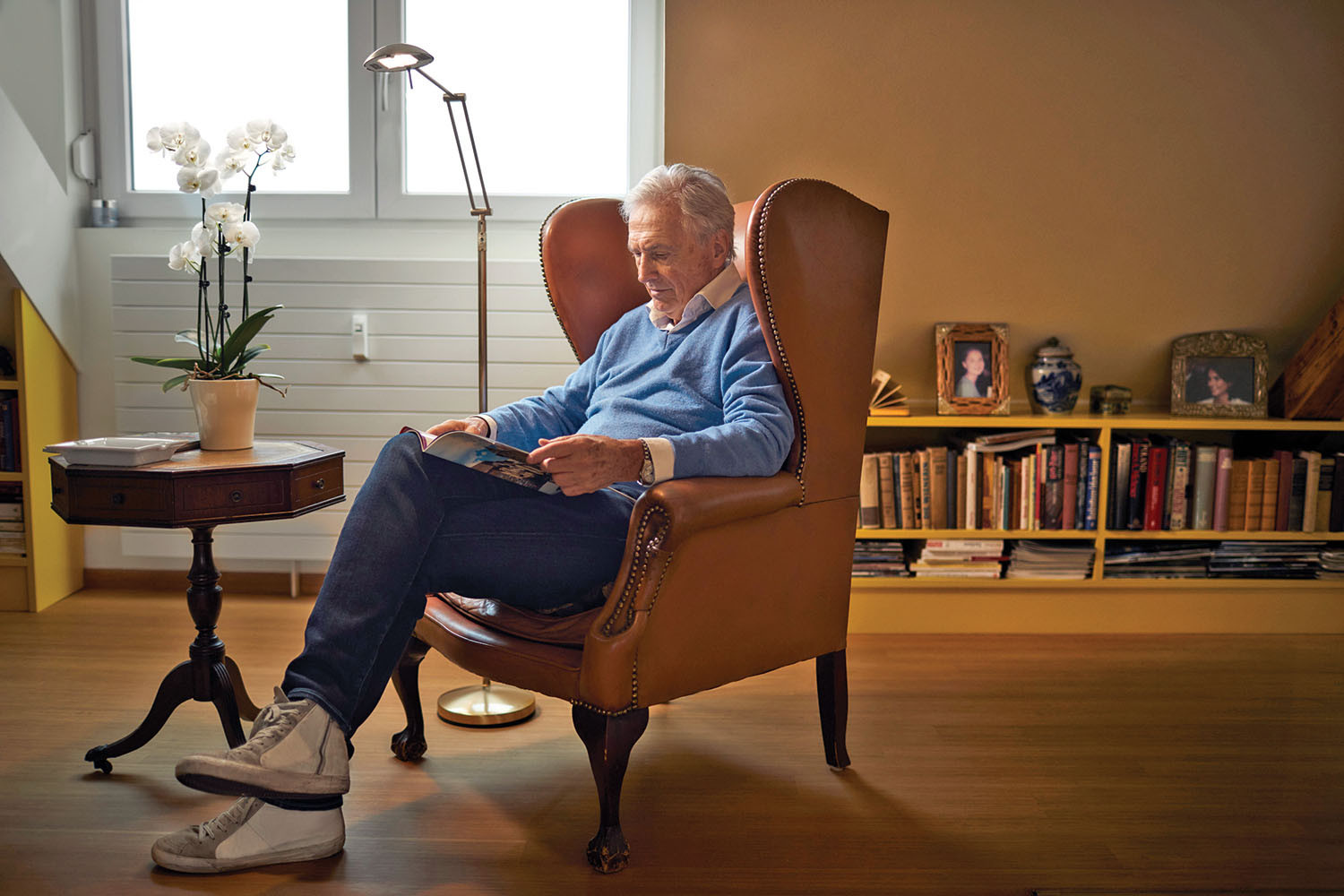 photo of a man sitting in a chair in his living room reading a book