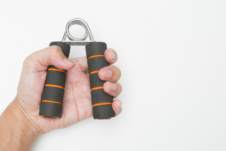 A photo of a close-up of a hand holding exercise equipment over white background. 