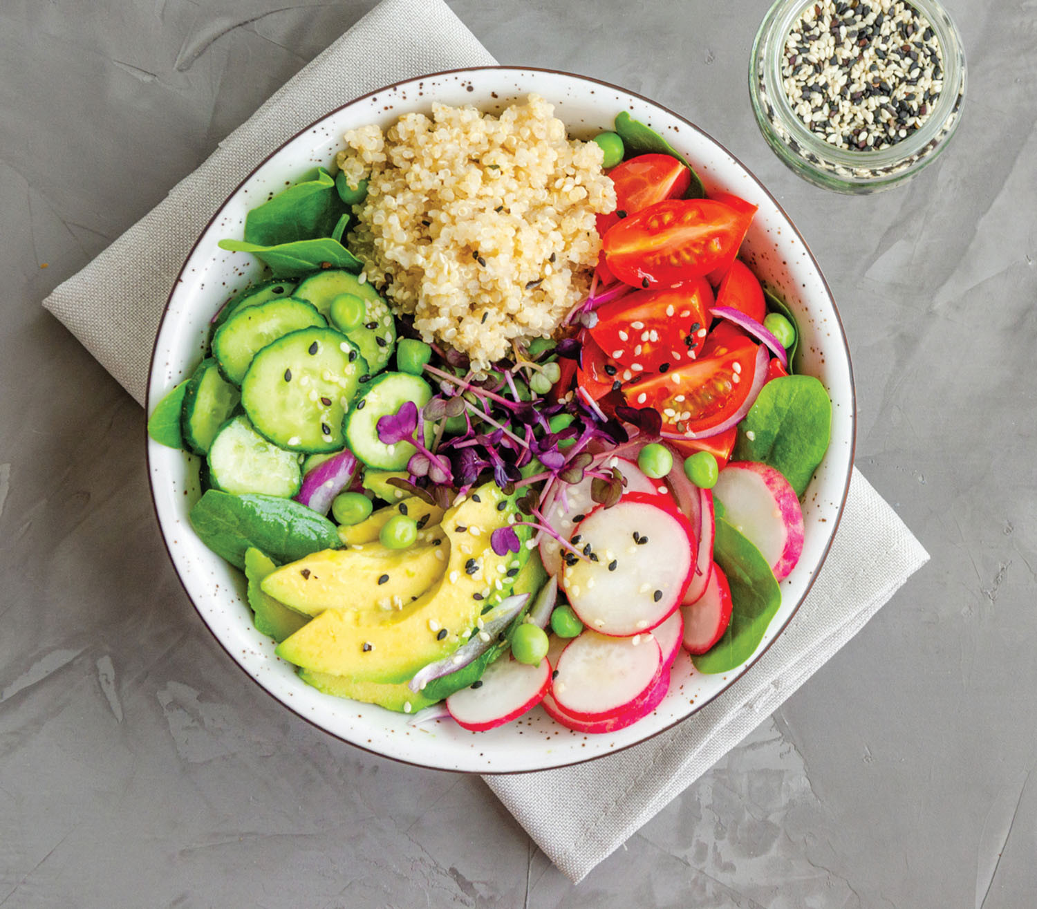 photo from above of a healthy salad that includes cucumber, radish, avocado, tomato, greens, and wild rice