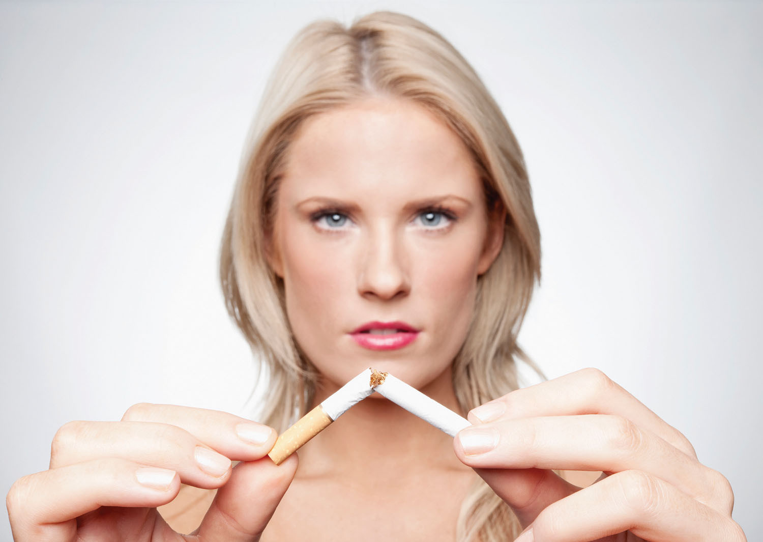 photo of a woman breaking a cigarette in half while looking directly at the camera