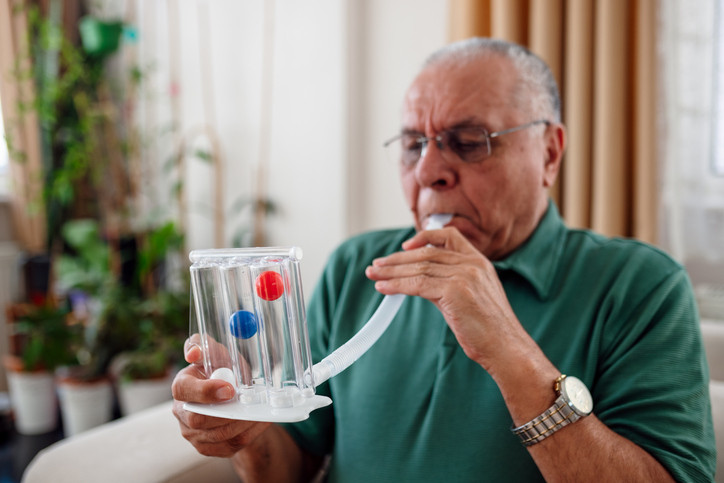 An image of a patient measures his own lung capacity. 