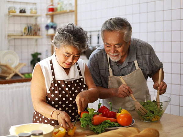 A couple cooking a meal with lots of vegetables together