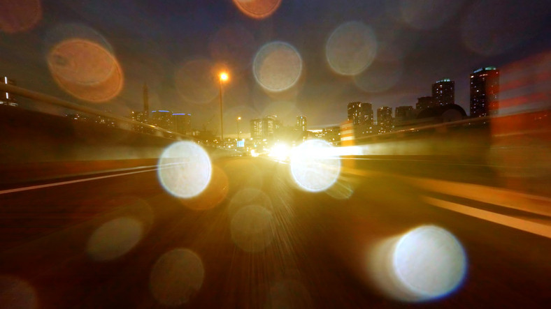 Abstract of traffic on city highway at night with glaring headlights forming big, colored dots 