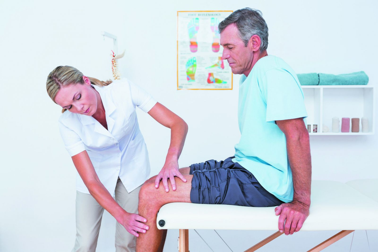 A mature man having his knee examined by a healthcare professional.