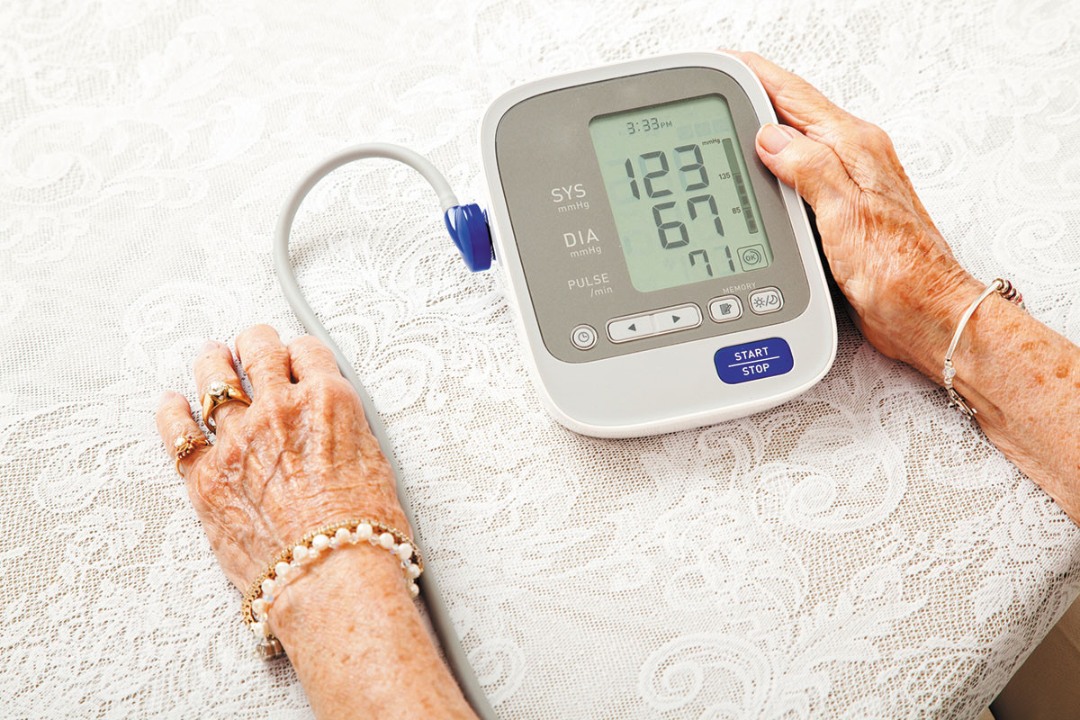 cropped photo of a woman using a home blood pressure device; only her hands and the device are visible