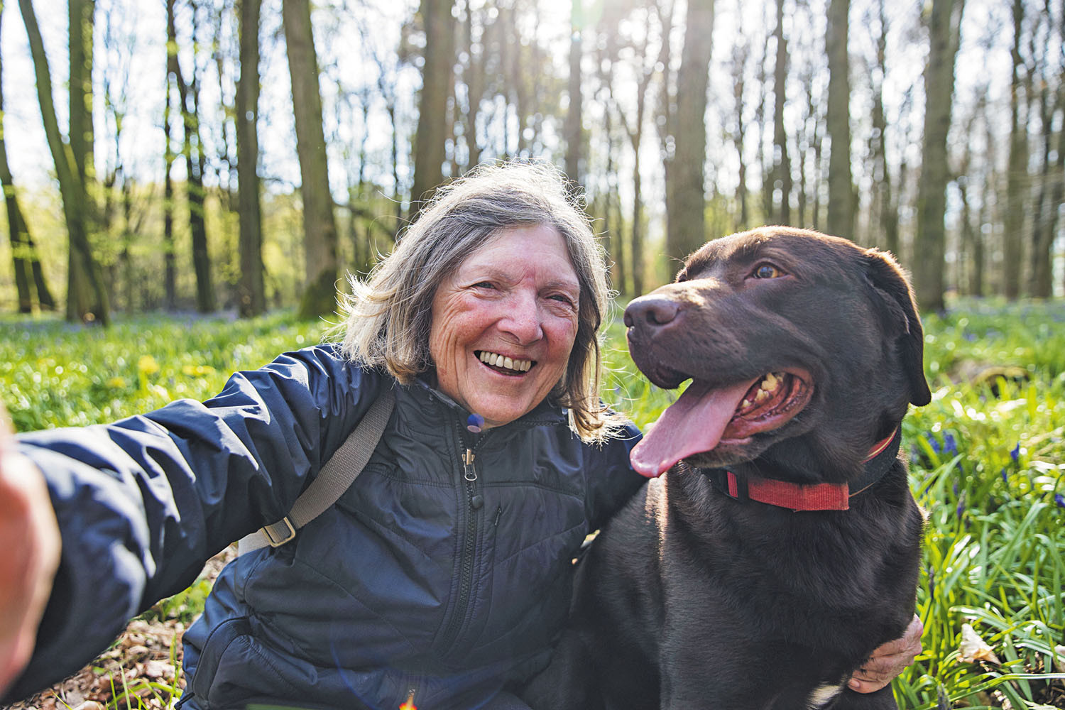 photo of a woman taking a selfie of herself and her dog, outdoors in a field
