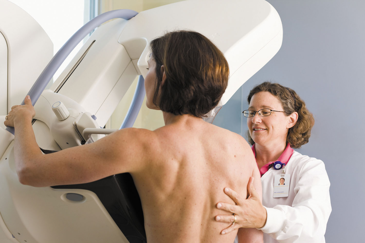 photo of a technician guiding a woman into position for a mammogram