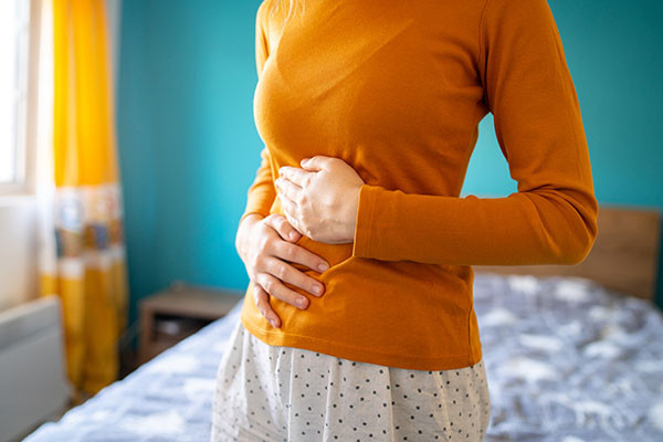 cropped photo showing the torso of a woman holding her stomach due to pain