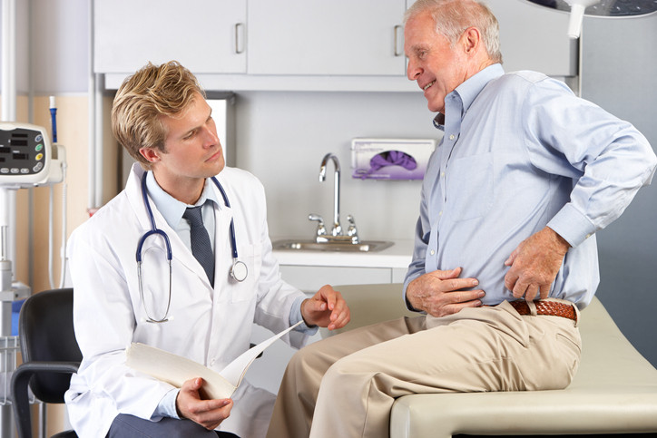 Doctor examining male patient with hip pain.