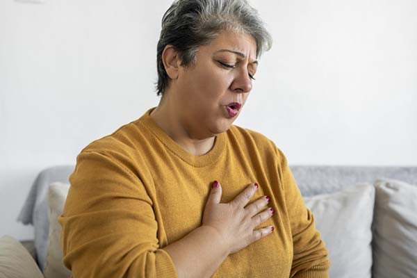 photo of a woman holding her hand over her chest, experiencing pain