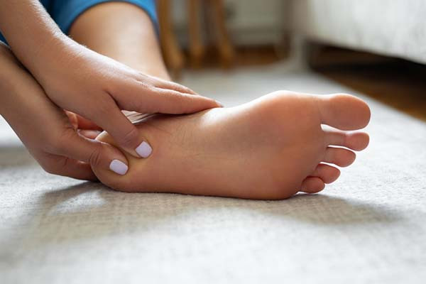 cropped photo showing a woman's foot and her hands massaging the heel