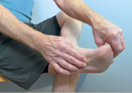 photo of a person holding his foot with both hands while performing a plantar fascia stretch exercise