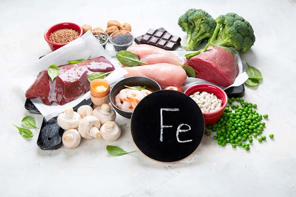 photo of an assortment of foods that are high in iron, includinfg chicken, beef, shrimp, beans, mushrooms, broccoli, nuts, eggs, and seeds