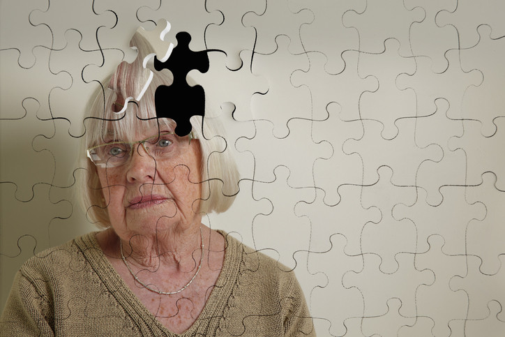 photo of a senior woman with a melancholy expression; the image has lines to make it look like a puzzle, and a piece of the woman's head has been removed and set askew