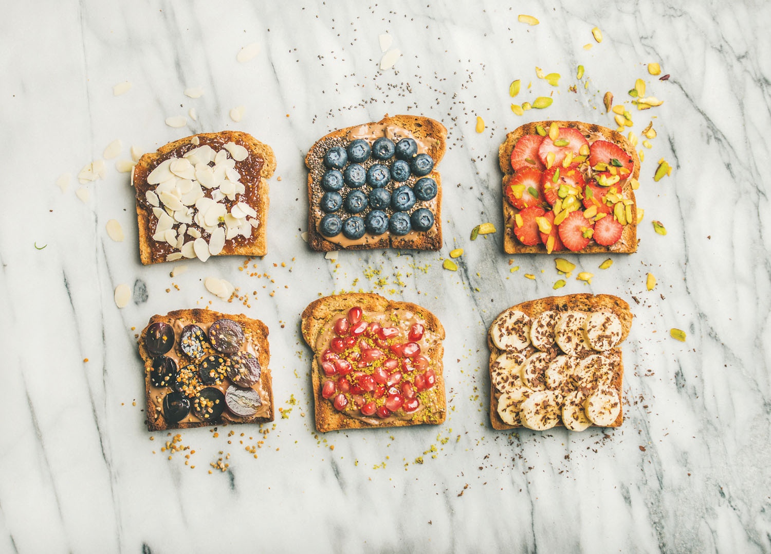six slices of toast shown with a variety of nut butters and fruits on them