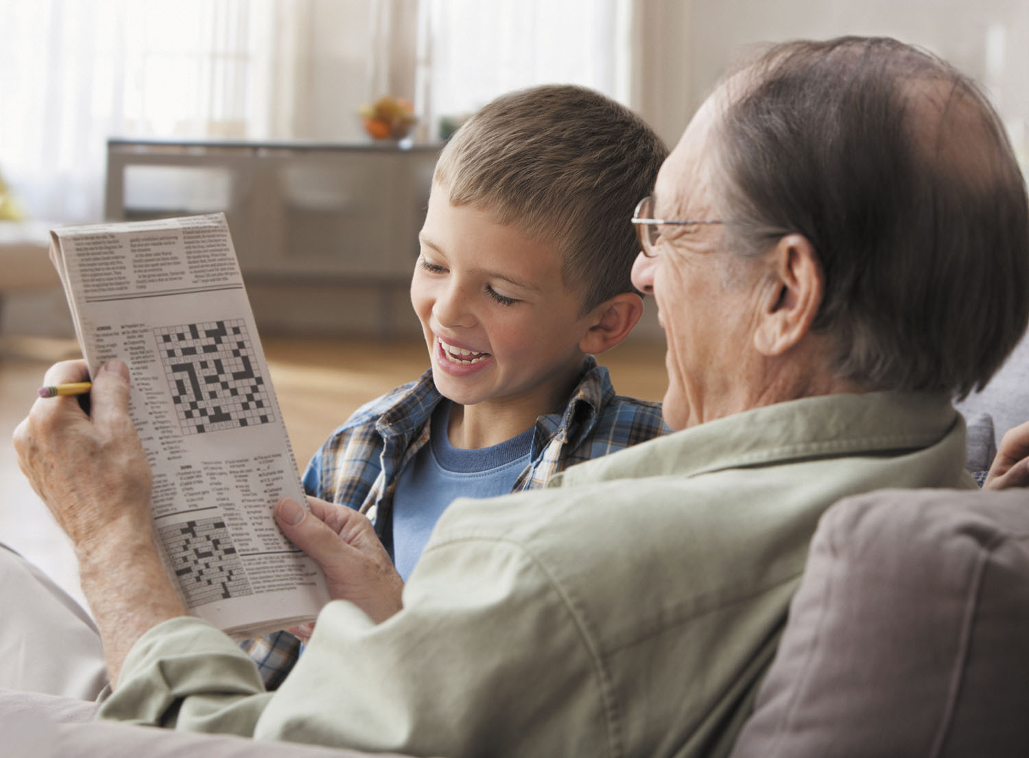 photo of a grandfather and grandson working on a newspaper crossword puzzle together
