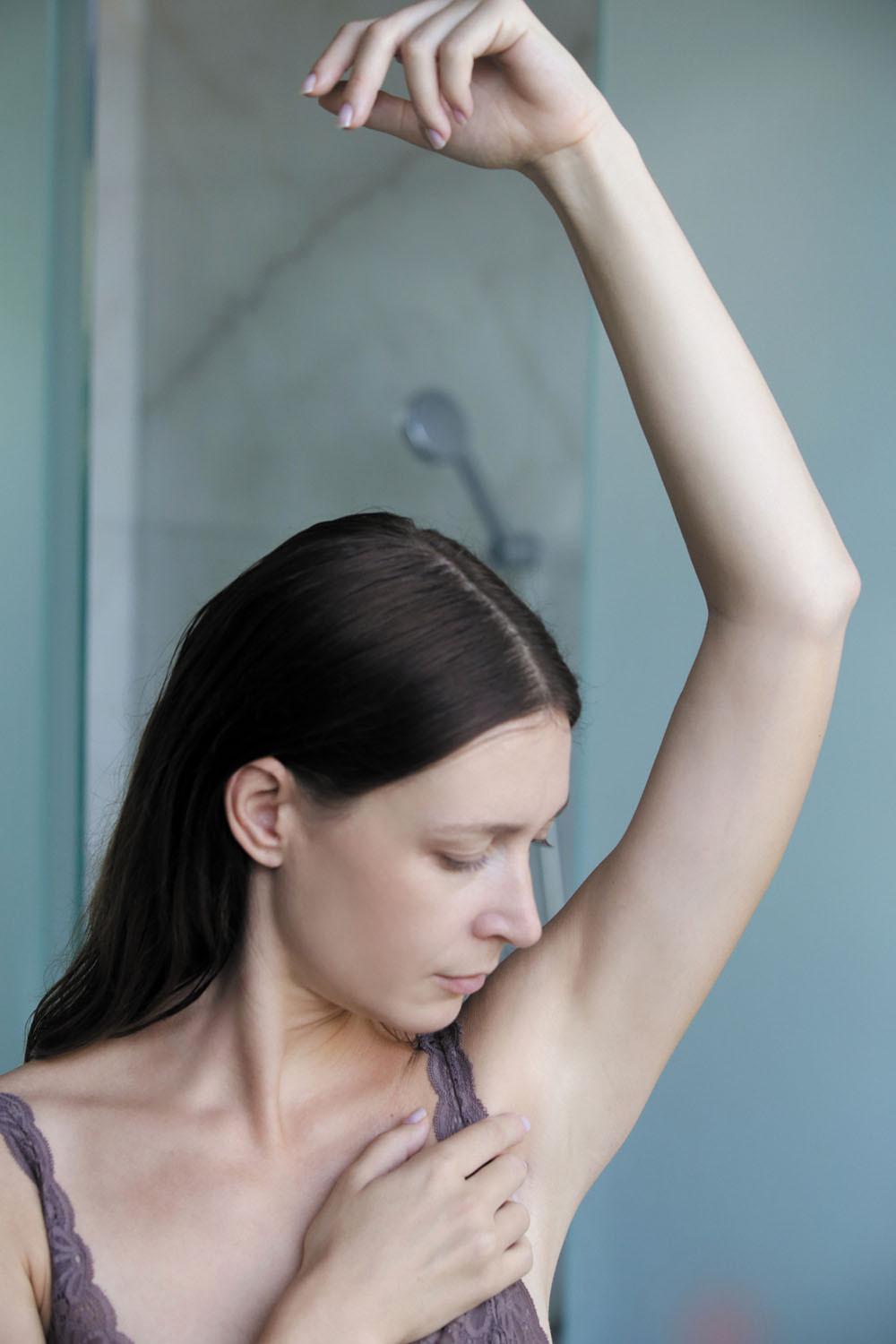 photo of a woman holding up her arm and smelling her armpit