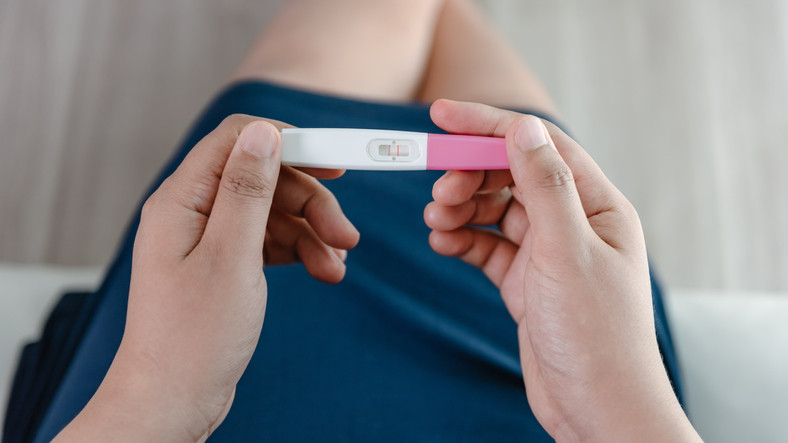 photo looking down on the hands of a woman holding a pregnancy test showing two red lines