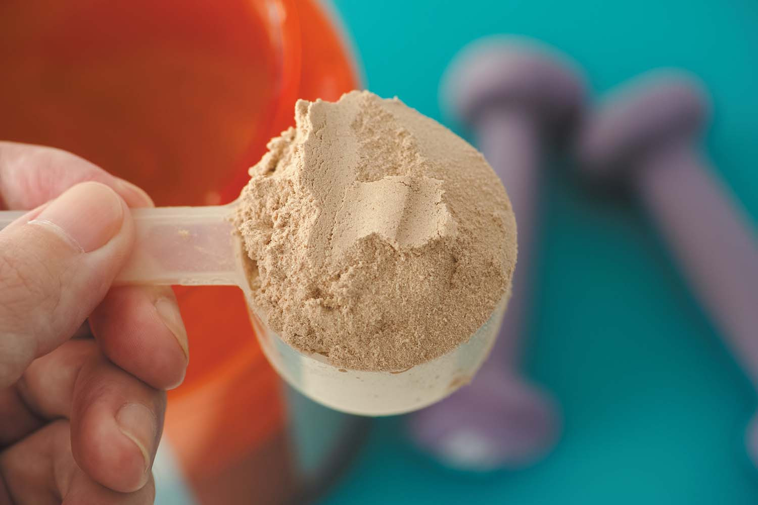 close-up photo of a scoop of protein powder held by a hand
