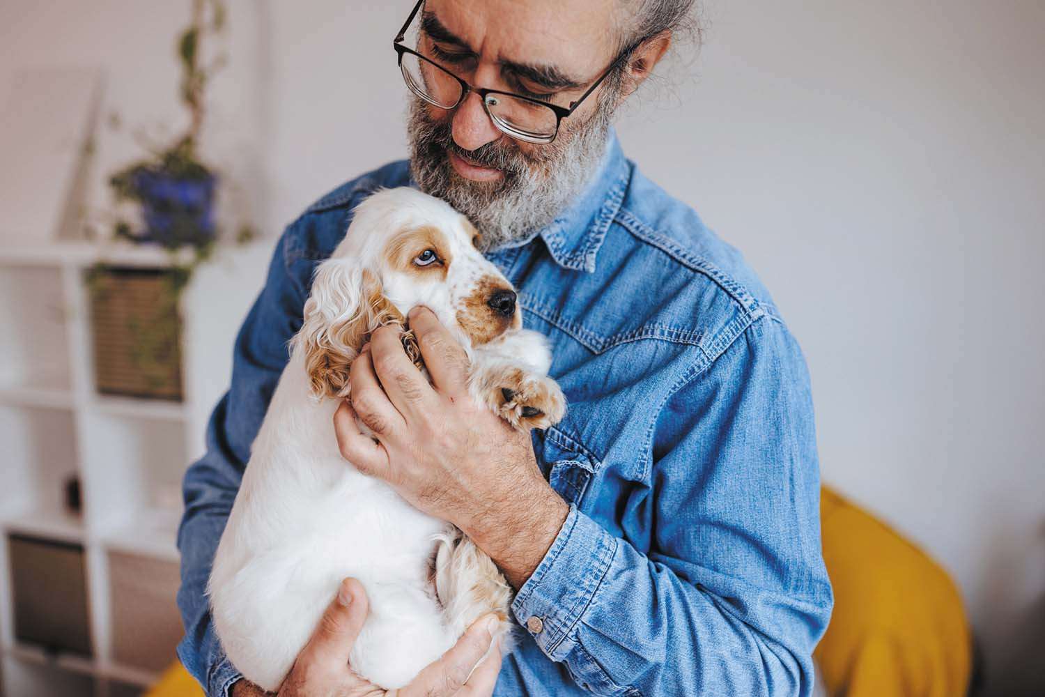 photo of a man holding a white and tan puppy to his chest