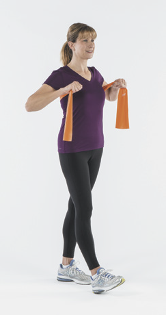 photo d'une femme tenant un élastique orange en position de départ pour l'exercice de coups de poing à la poitrine tel que décrit dans l'article