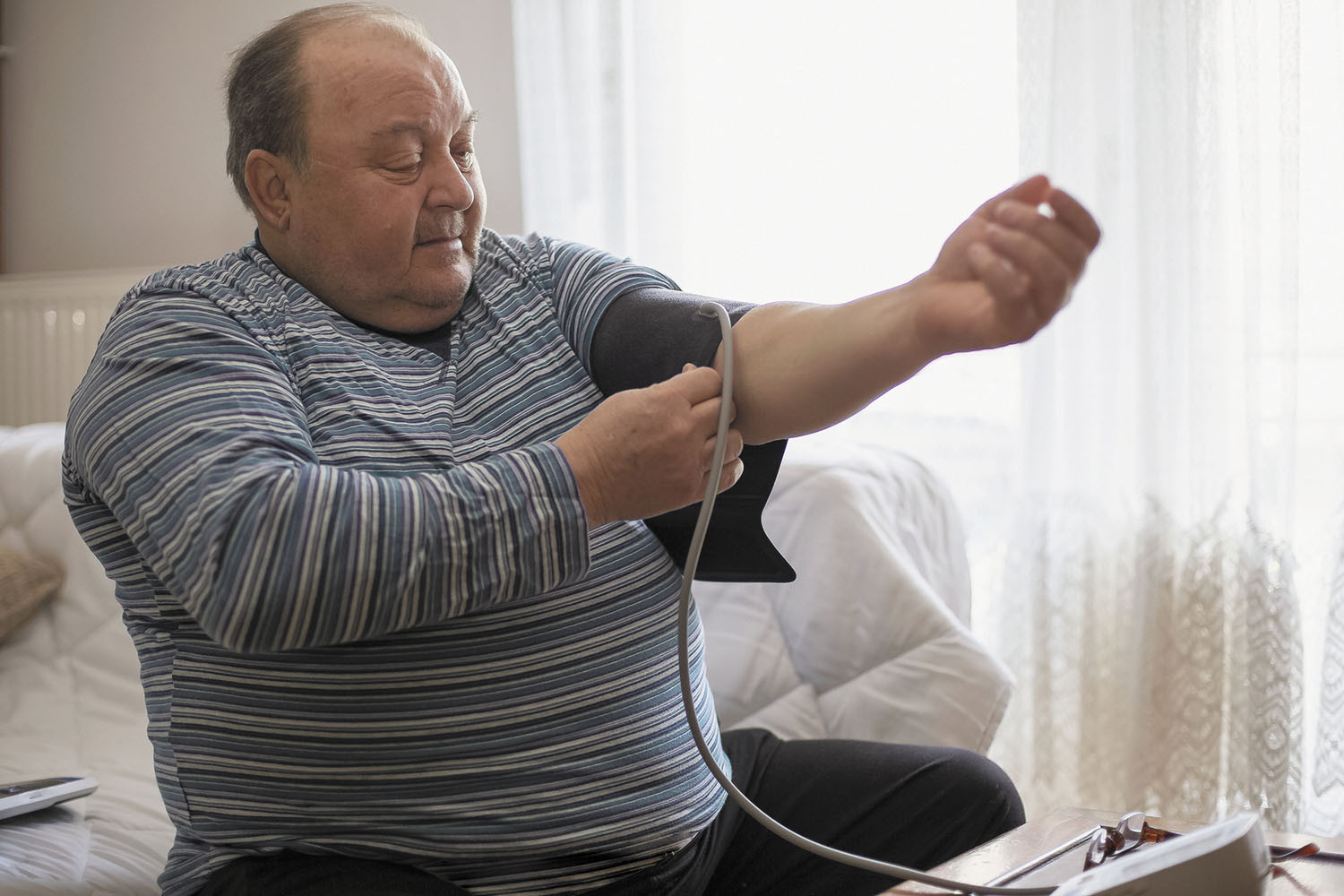 photo of a large man putting a blood pressure cuff on his left arm