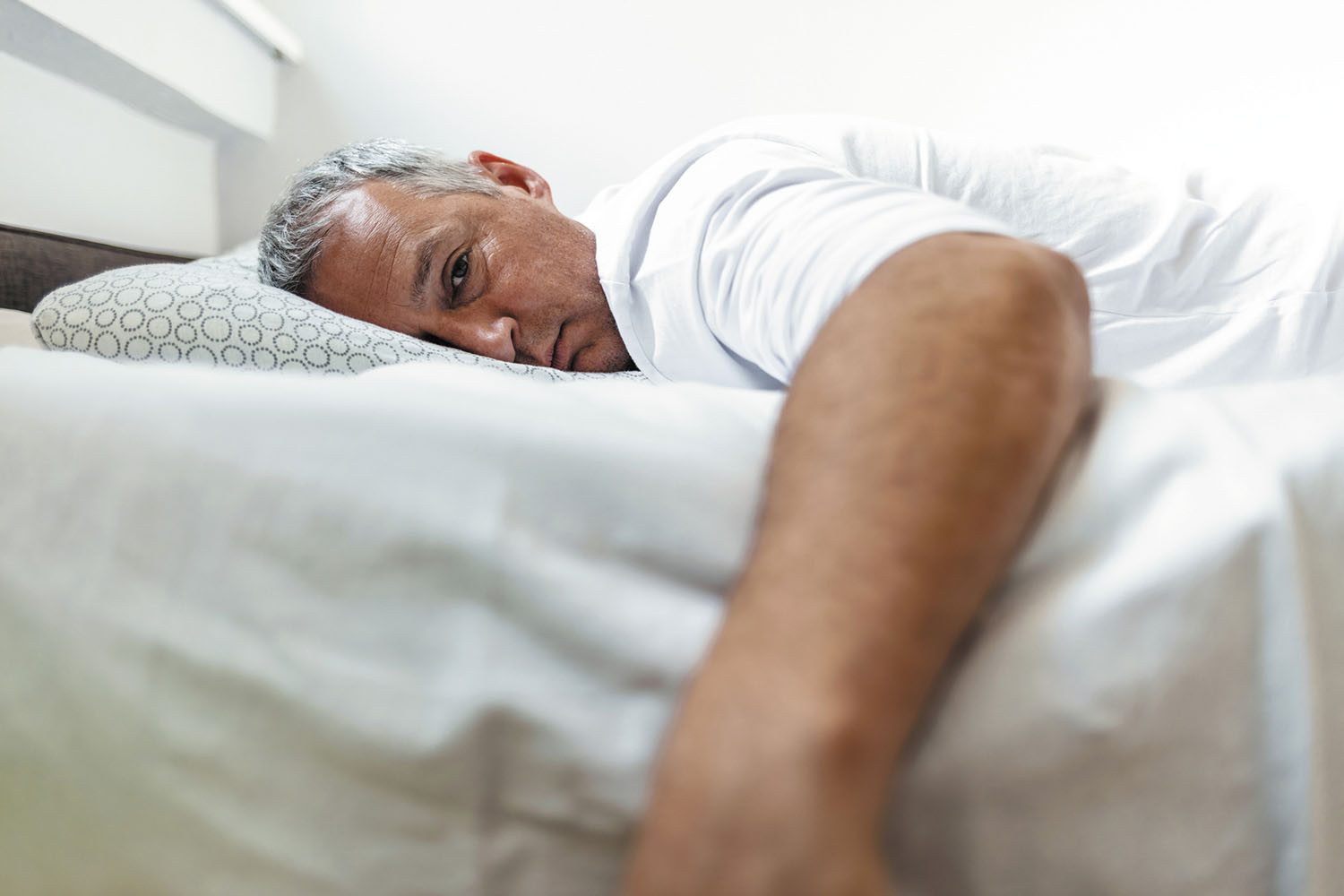 photo of a man awake in bed, unable to fall asleep