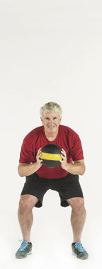 Image of a man holding a medicine ball in the starting position for squat and overhead toss exercises