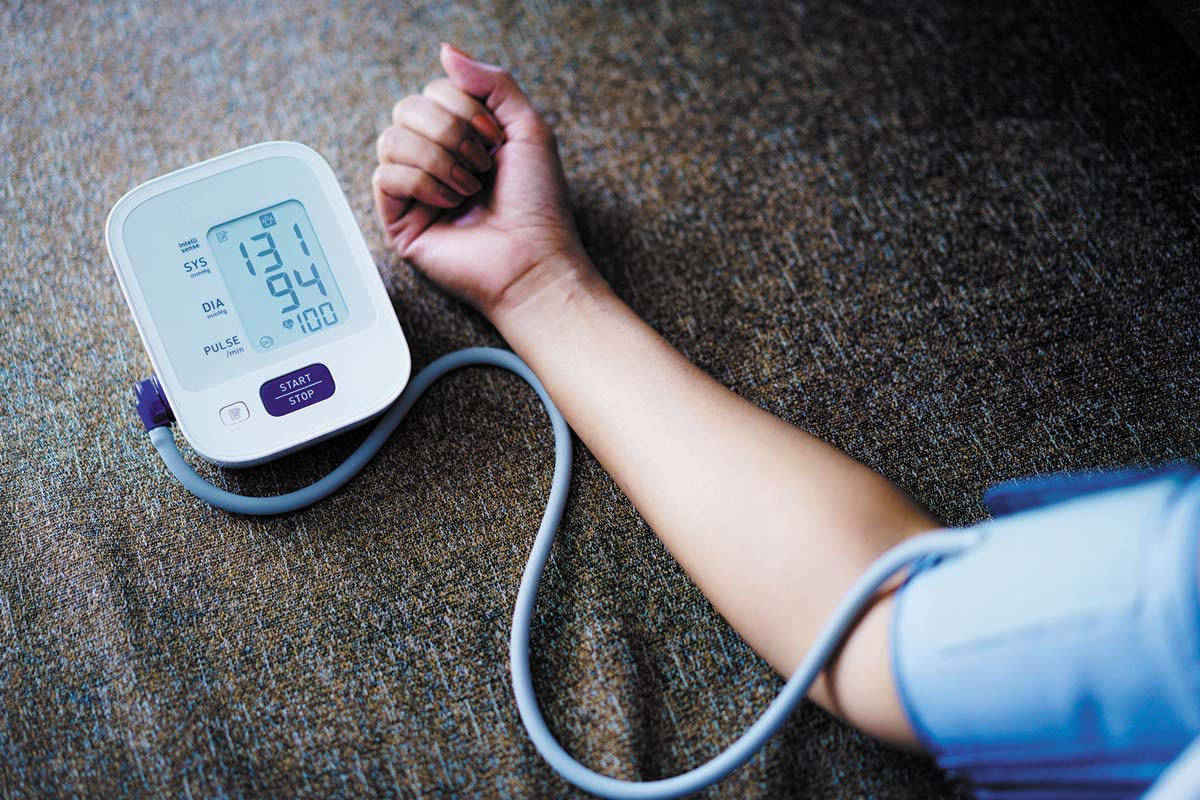 photo of a home blood pressure monitor and the arm of a person using it