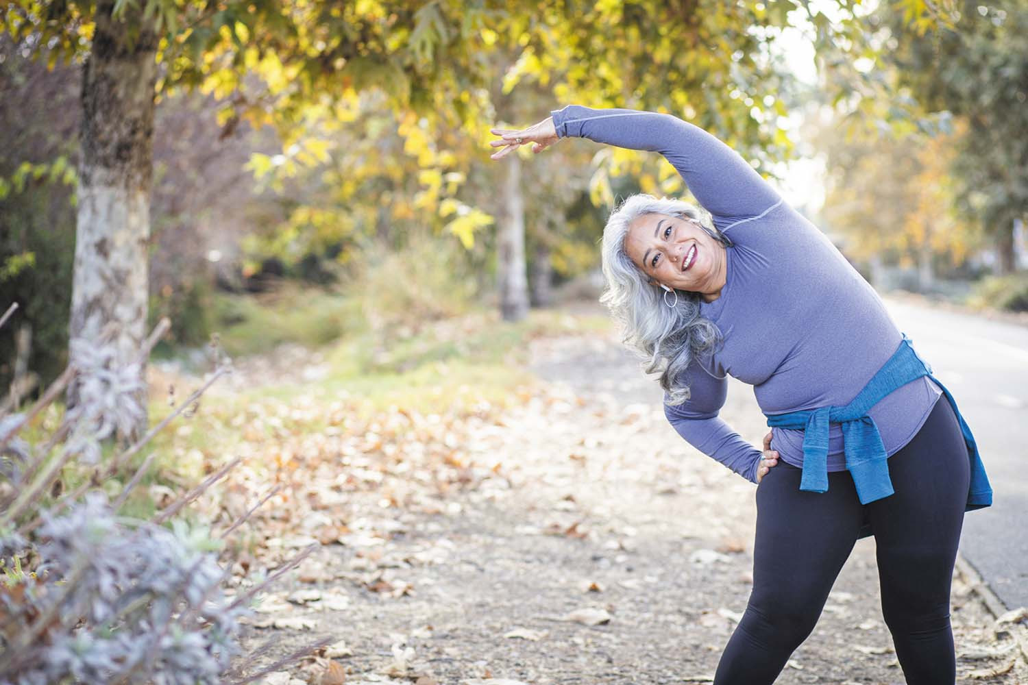 photo of a woman doing side stretches outdoors on a trail