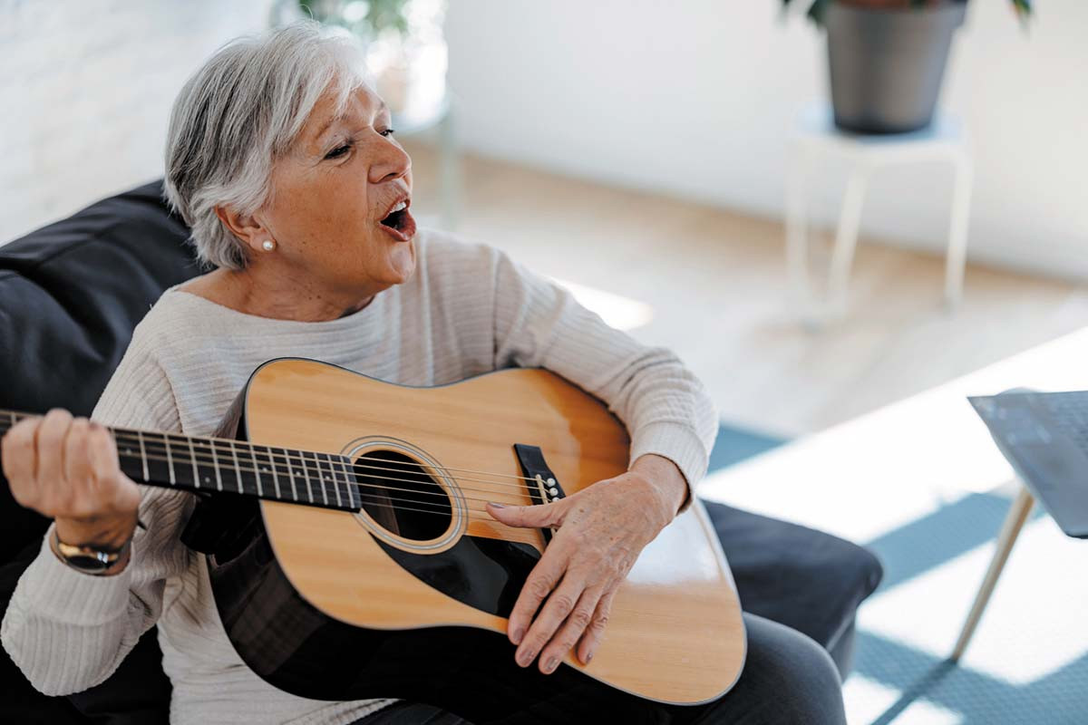 photo of a mature woman singing while playing an acoustic guitar