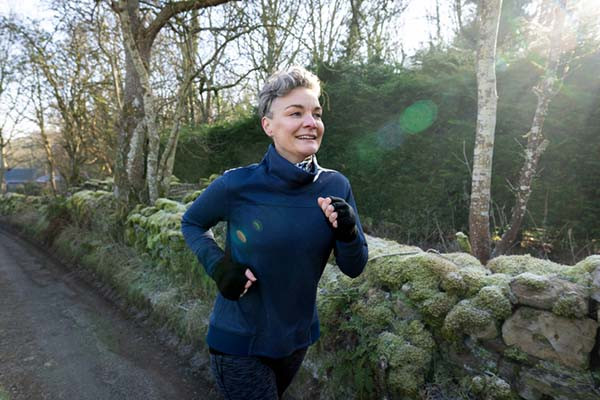 photo of a woman running on a country road during cold weather