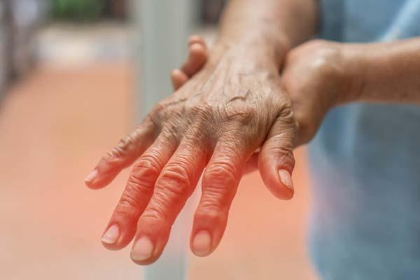 cropped photo of a person extending their hand palm down and holding the wrist with their other hand